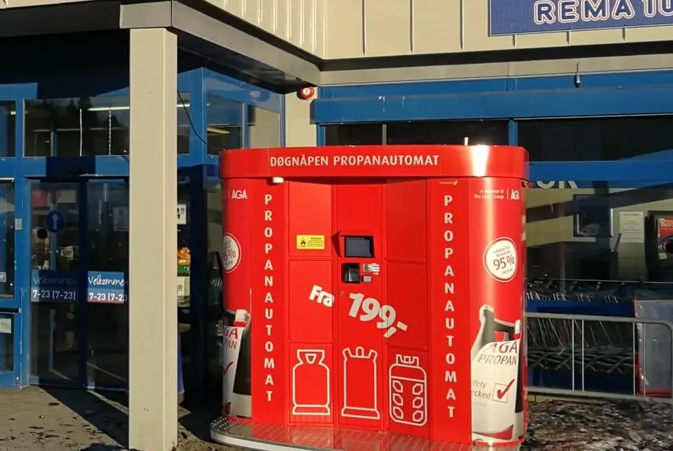 A red AGA-branded Vendanor Propane Vending Machine installed at a store entrance in Norway.
