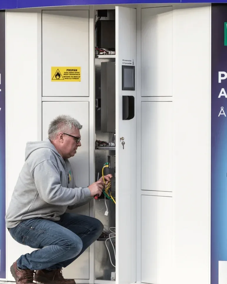Technician servicing the wiring inside an open Vendanor Propane Vending Machine.