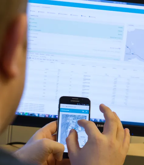 A person photographing a phone screen while viewing the Vendanor Connect management dashboard on a monitor.