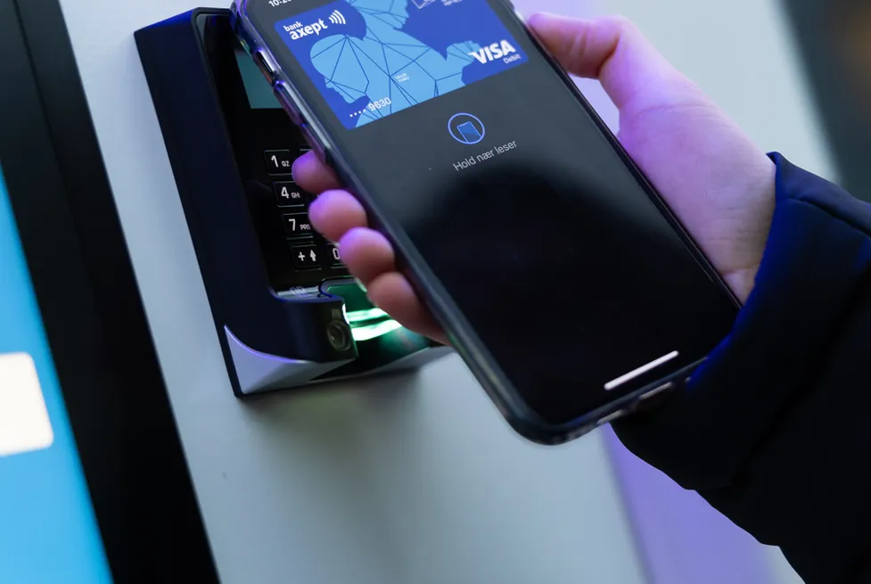 A hand making a contactless smartphone payment at the card terminal of a Vendanor machine.