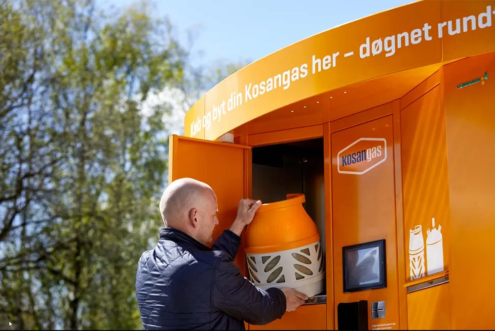 A man exchanging an orange Kosangas propane cylinder at a Vendanor Propane Vending Machine outdoors.