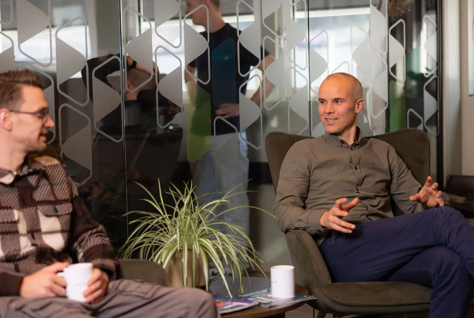 Two colleagues having a relaxed conversation in a modern Vendanor office lounge.