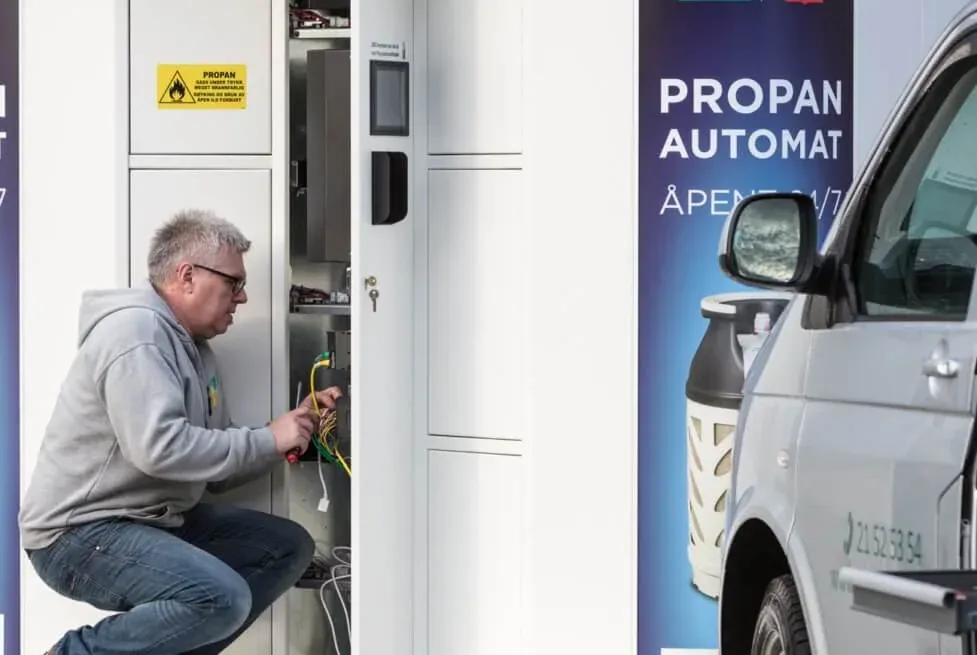 Technician performing annual service on the open electrical cabinet of a Vendanor Propane Vending Machine.