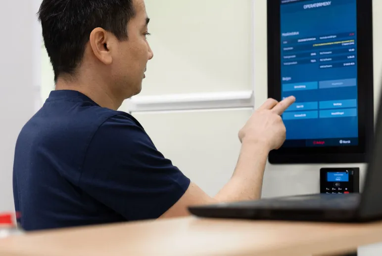 Vendanor employee performing quality control at a touchscreen workstation.