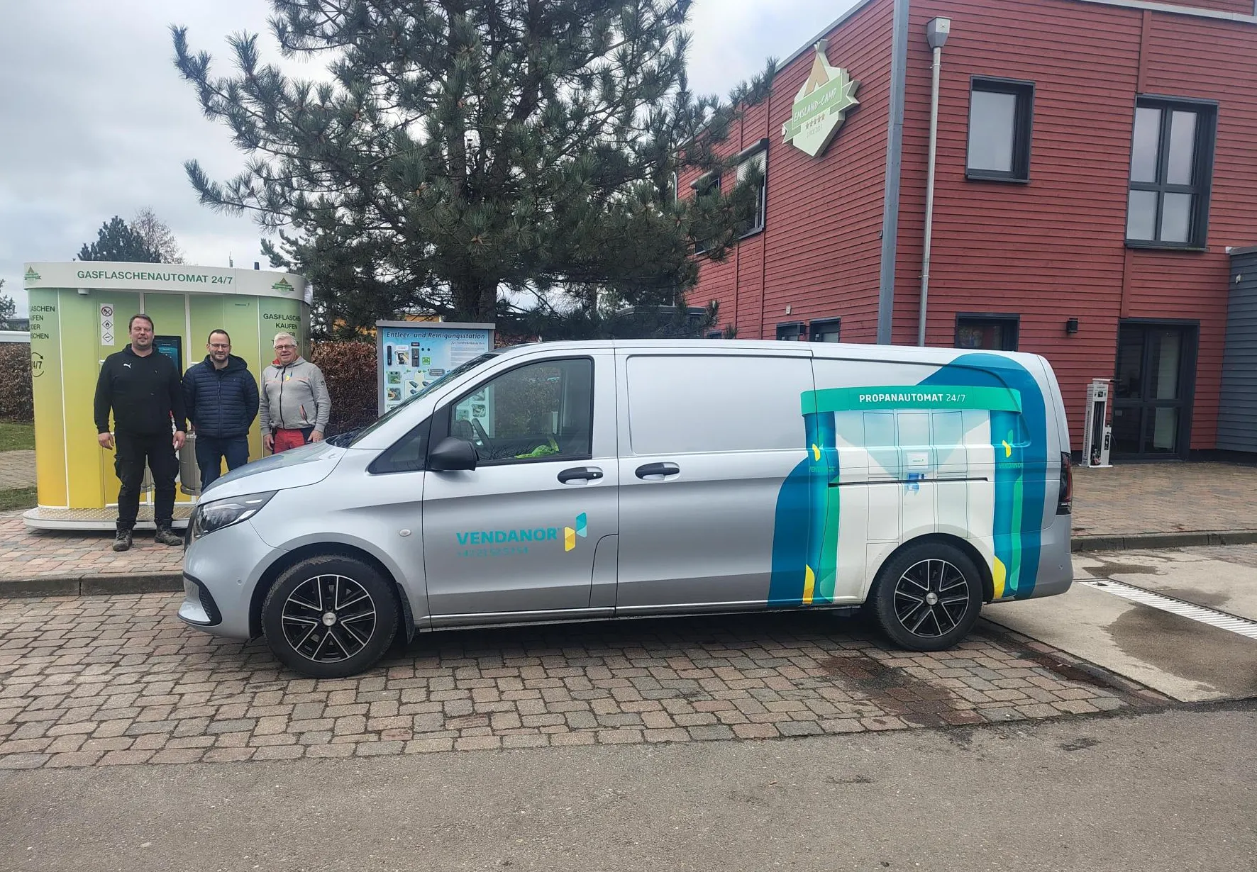 Vendanor branded service van parked beside a Propane Vending Machine with staff outside a building.