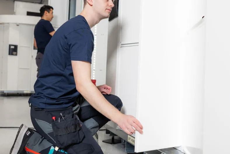Two Vendanor technicians assemble white machine cabinets on the production floor.